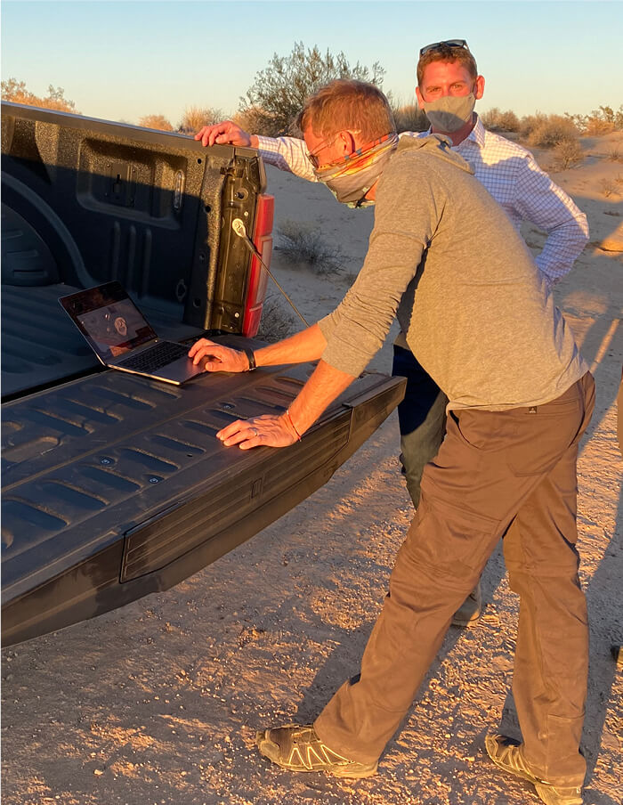 Men reviewing laptop on truck trunk